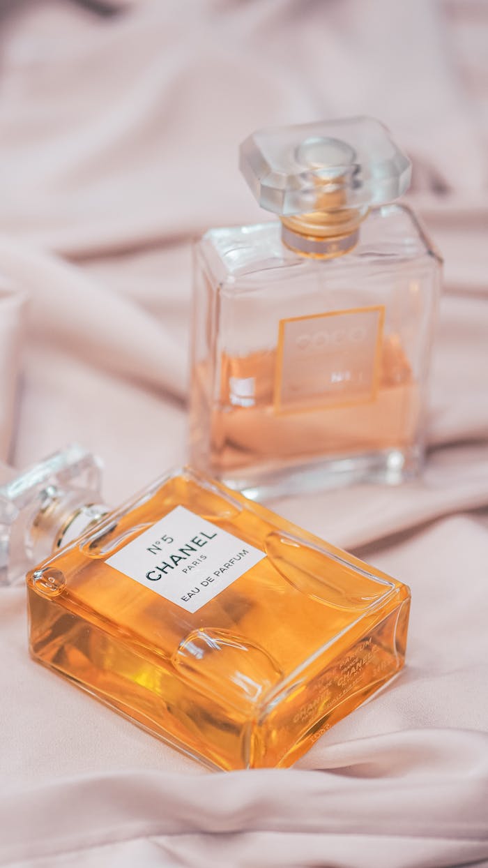 Stylish vertical shot of Chanel perfumes on soft fabric, Paris elegance.