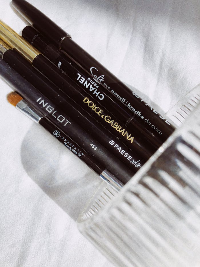 A collection of various brand makeup brushes in a glass holder, shot in soft lighting.